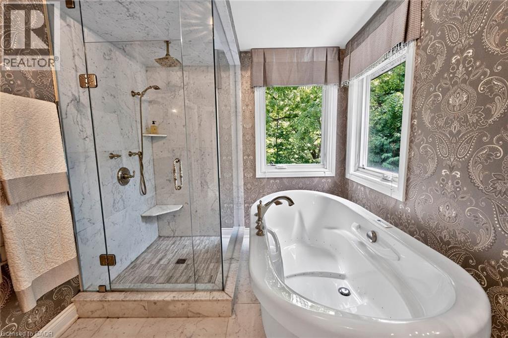 Freestanding soaking tub, walk-in shower with glass enclosure, integrated shower bench, dual windows, and ornate patterned wallpaper - 11 Christman Court, Markham, ON - Indoor Photo Showing Bathroom
