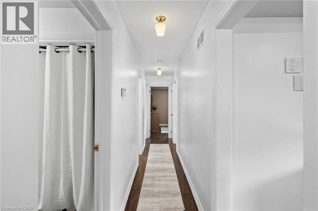 Hallway featuring dark wood-finish flooring, white walls, and flush-mount lighting fixtures - 1083 Melton Drive, Mississauga, ON