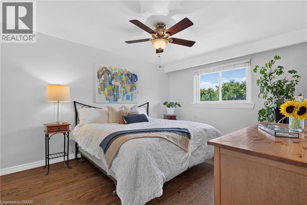 Wood-finish flooring with a white trimHardwood-finish flooring, ceiling fan with integrated lighting, white window trim, and light wall paint - 1083 Melton Drive, Mississauga, ON