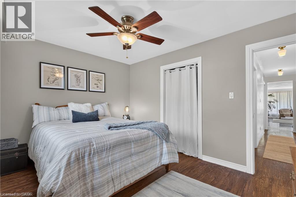 2nd bedroom features neutral wall tones, wood-finish flooring, ceiling fan with integrated lighting, and a closet with a curtain enclosure - 1083 Melton Drive, Mississauga, ON