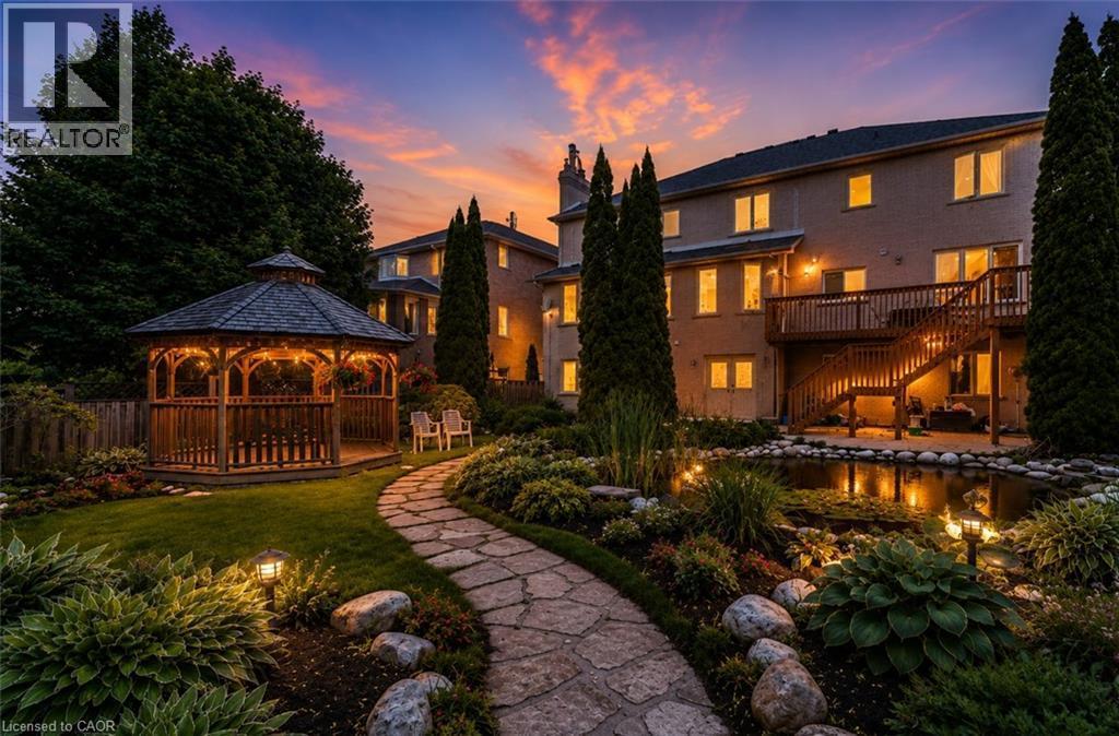 Expansive backyard featuring a stone pathway, a wooden gazebo, a tiered wooden deck with stairs, a decorative pond, and extensive landscaping - 23 Susan Drive, Hamilton, ON