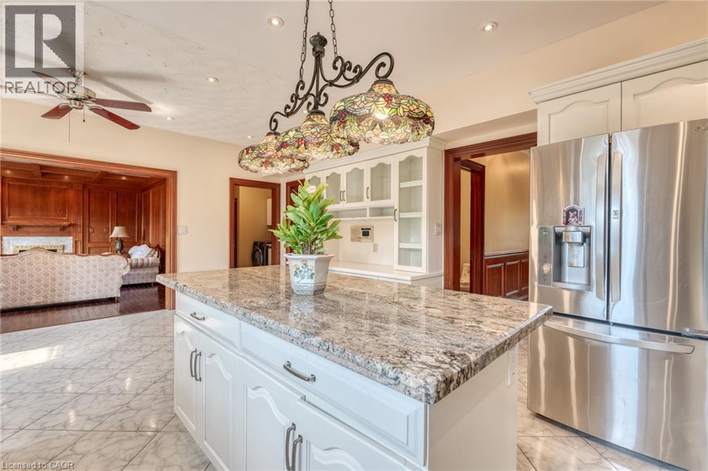 Kitchen island with a granite countertop, white cabinetry, and decorative pendant lighting - 23 Susan Drive, Hamilton, ON