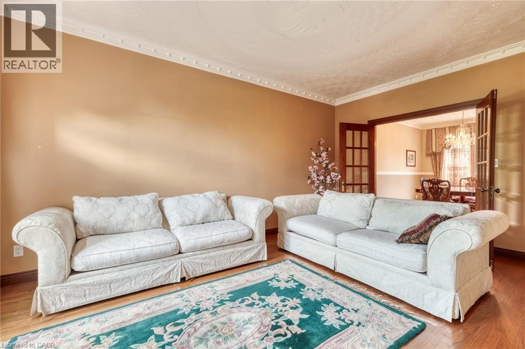 Hardwood-style flooring, crown molding, and French doors with glass panels create an inviting atmosphere - 23 Susan Drive, Hamilton, ON