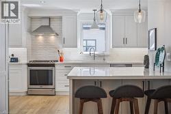 White cabinetry, stainless steel range with matching hood, subway tile backsplash, and light-toned wood-finish flooring - 