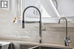 Double basin stainless steel sink, polished chrome gooseneck faucet, separate filtered water faucet, quartz-finish countertop, and white subway tile backsplash - 
