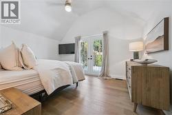 Varnished wood-finish flooring, vaulted ceiling, built-in ceiling fan, and French doors - 