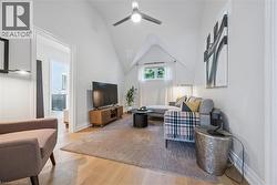 Vaulted ceiling with a ceiling fan, recessed window, light wood-finish flooring, and a built-in media console - 