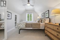 Bright room featuring sloped ceilings, recessed shelving, a window with exterior views, and a ceiling fan - 
