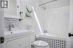 Bright and updated bathroom featuring a floating vanity with a rectangular vessel sink, subway tile backsplash, and matte black fixtures - 