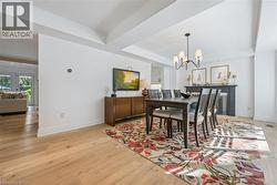Light wood-finish flooring, white walls, and a recessed ceiling design with a black metal chandelier - 