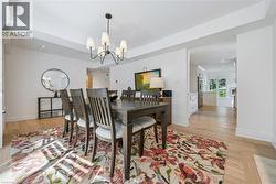 Dining area featuring wood-finish flooring, a tray ceiling, and a multi-arm chandelier - 