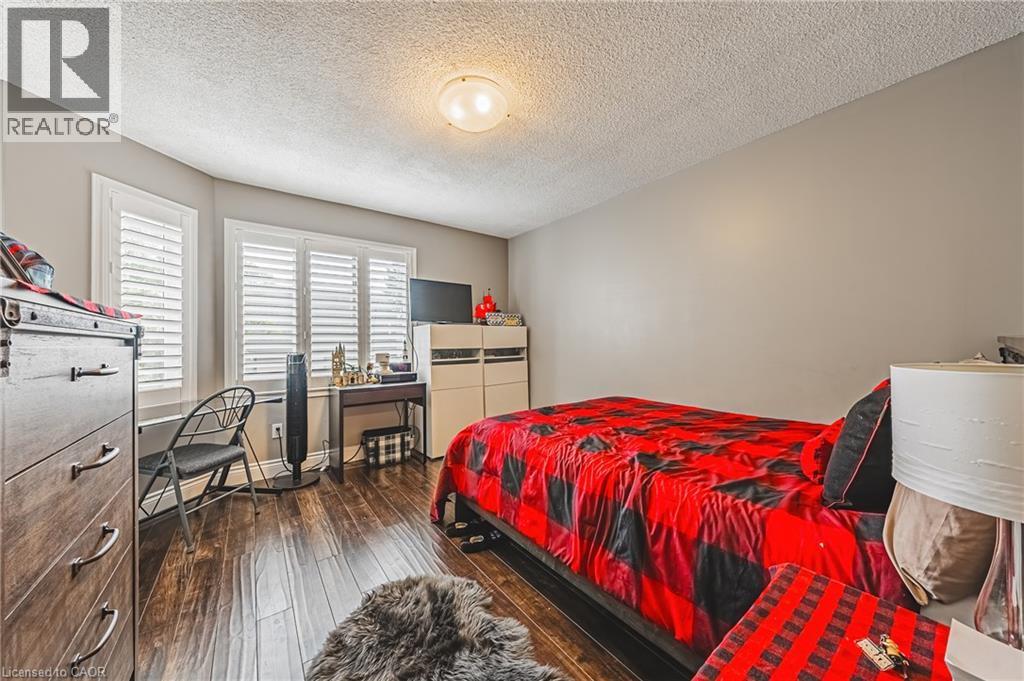 Wood-finish flooring, multiple windows with louvered shutters, and a ceiling-mounted light fixture - 266 Limeridge Road E Unit# 3, Hamilton, ON