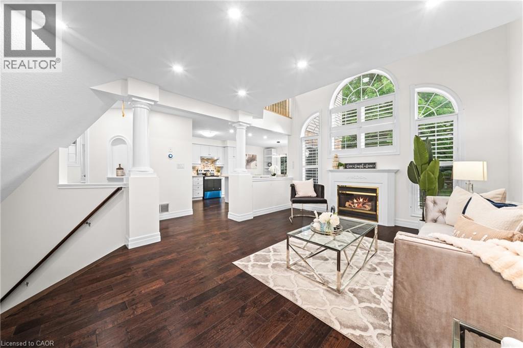 Recessed lighting, wood-finish flooring, white fireplace with mantel, arched windows with shutters, and architectural columns - 495 Brigantine Drive, Waterloo, ON