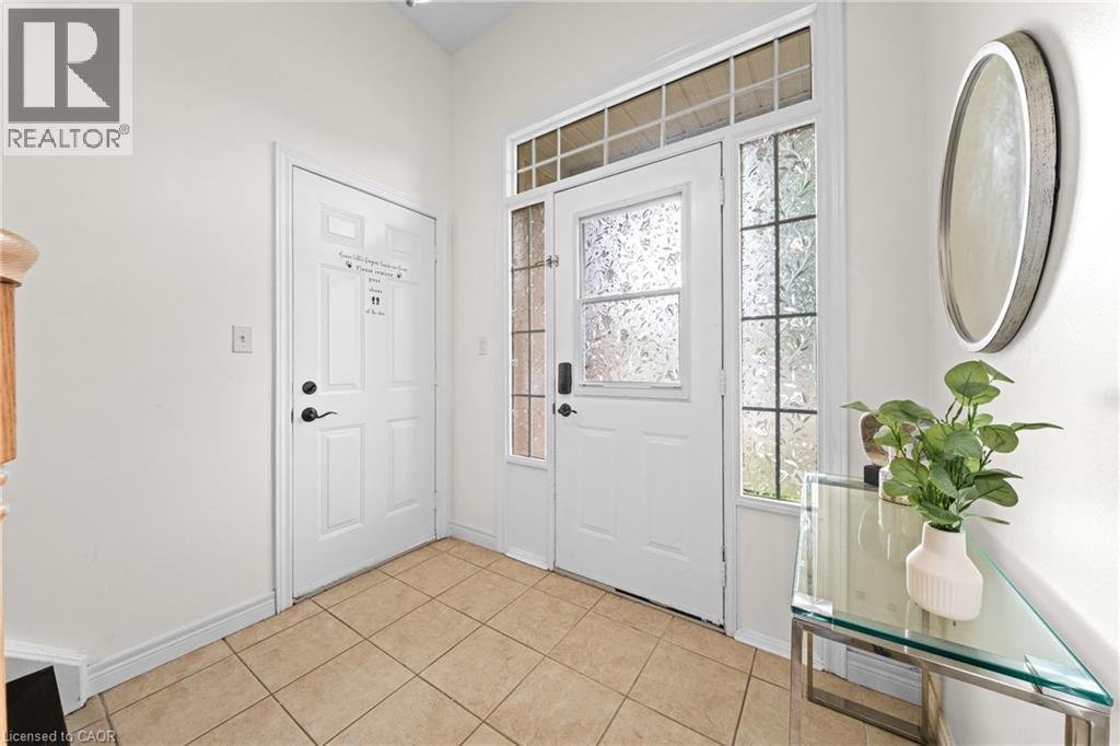 Entryway featuring a main door with decorative glass, two side panels with textured glass, a transom window, and square tile flooring - 495 Brigantine Drive, Waterloo, ON