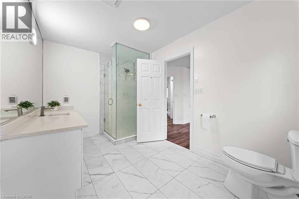 Bathroom featuring a glass-enclosed shower, white vanity with an undermount sink, light-toned countertop, and large format tile flooring - 495 Brigantine Drive, Waterloo, ON