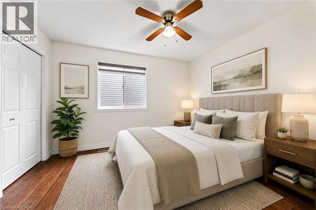 Wood-finish flooring, ceiling fan with integrated lighting, white bi-fold closet doors, and window with blinds - 495 Brigantine Drive, Waterloo, ON