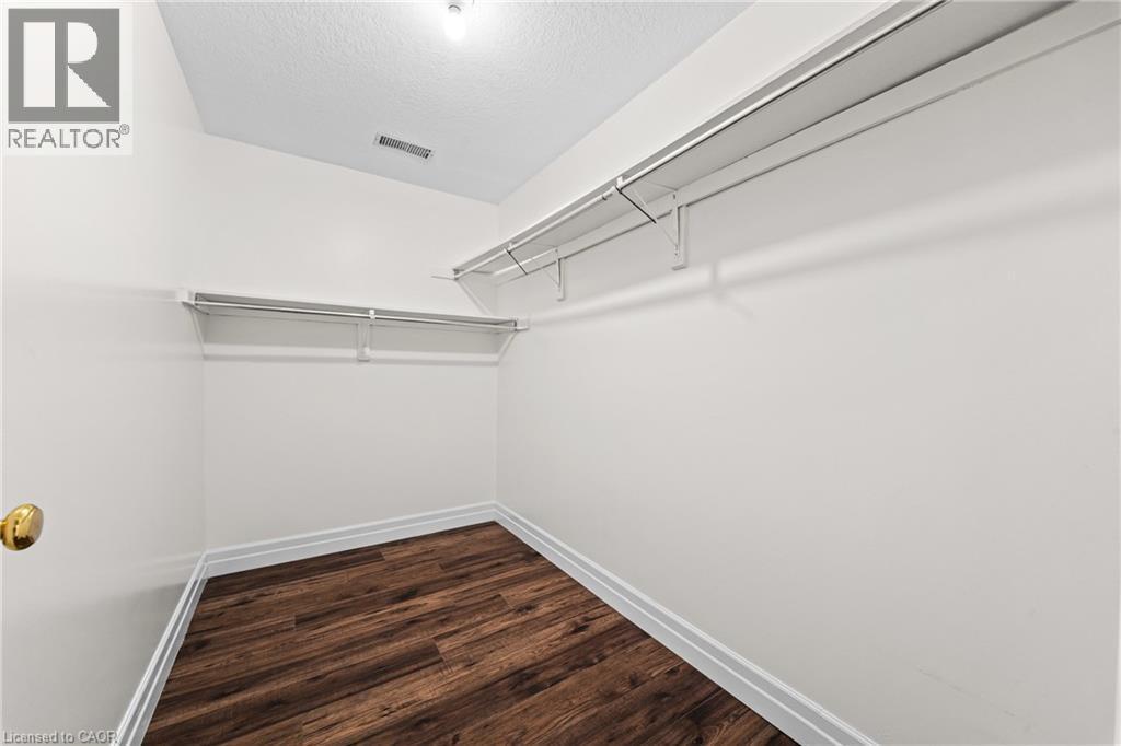 White walls with wood-finish flooring, featuring a built-in closet organization system - 495 Brigantine Drive, Waterloo, ON