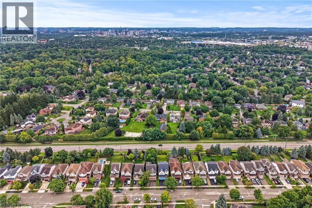 Aerial view showcasing a tree-lined residential community with mature landscaping, established neighborhoods extending toward the downtown skyline, and a tree-canopied streetscape with consistent sing - 495 Brigantine Drive, Waterloo, ON