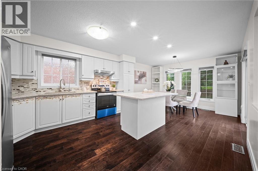 White cabinetry, wood-finish flooring, recessed lighting, central island with seating, and integrated shelving - 495 Brigantine Drive, Waterloo, ON