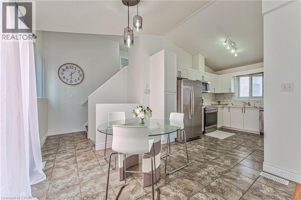 Kitchen featuring white cabinetry, stainless steel appliances, and a tile backsplash - 168 Copper Leaf Street, Kitchener, ON
