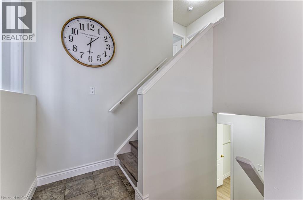 Stairwell featuring a neutral color palette, tile flooring, and a white handrail - 168 Copper Leaf Street, Kitchener, ON