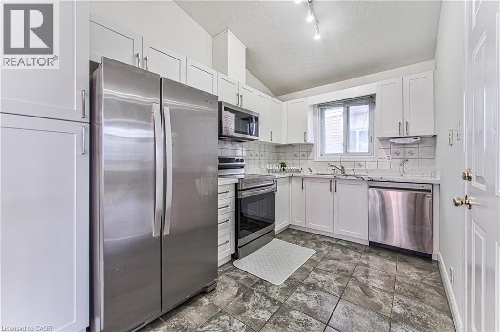 Kitchen featuring white cabinetry, stainless steel appliances, tile flooring, and a window - 168 Copper Leaf Street, Kitchener, ON