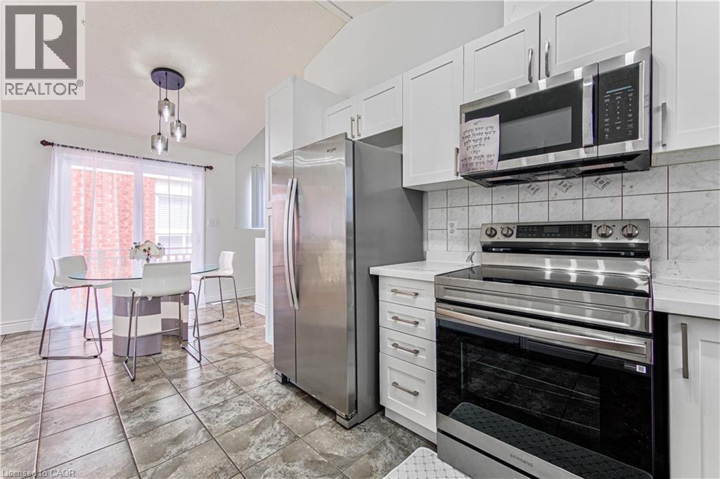 Kitchen featuring stainless steel appliances, white cabinetry, a tiled backsplash, and stone-look flooring - 168 Copper Leaf Street, Kitchener, ON