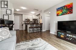 Open-concept living space with wood-finish flooring, recessed lighting, and a kitchen featuring stainless steel appliances, light cabinetry, and a breakfast bar with pendant lighting - 