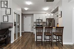 Kitchen featuring stainless steel appliances, light cabinetry, and an eat-in peninsula with pendant lighting - 