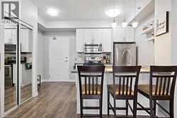 Kitchen featuring white shaker cabinetry, stainless steel appliances, a tile backsplash, and a breakfast bar with pendant lighting - 