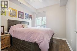 Wood-finish flooring, large window with roller shade, built-in bed frame storage, ceiling fan, and neutral wall tones - 