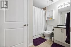 Full bathroom featuring a white vanity with dark countertop, built-in medicine cabinet, and tile flooring - 