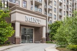Contemporary building exterior featuring a prominent main entrance with glass doors, a brick facade, and multiple upper-level balconies with glass railings - 