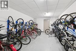 Dedicated bike storage room featuring wall-mounted racks, a drop ceiling, and recessed lighting - 