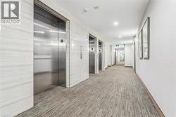 Hallway featuring multiple stainless steel elevators, patterned carpet flooring, and recessed ceiling lighting - 