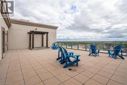 Expansive rooftop terrace with tile flooring, a dark wood pergola, and a glass-paneled railing - 