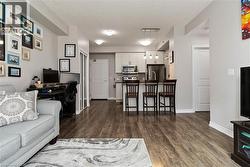 Open-concept living area featuring wood-finish flooring, recessed lighting, and a kitchen with stainless steel appliances - 