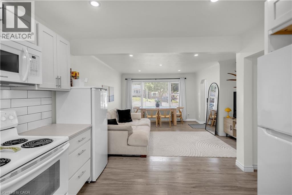 Open-concept living space featuring wood-finish flooring, white cabinetry, integrated microwave, and recessed lighting - 450 Highland Road E, Kitchener, ON