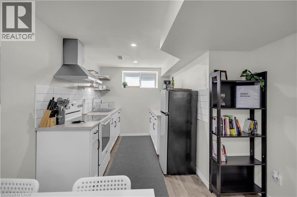 Contemporary kitchen featuring white cabinetry, subway tile backsplash, a stainless steel range hood, and a built-in electric range - 450 Highland Road E, Kitchener, ON