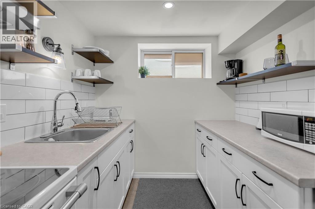 Lower Level Kitchen featuring white shaker-style cabinetry, a stainless steel sink with a high-arc faucet, and light-toned countertops - 450 Highland Road E, Kitchener, ON