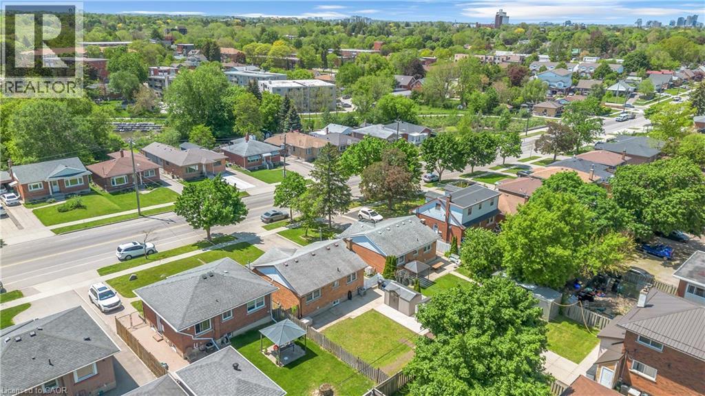 Aerial perspective showcasing a residential street with mature trees and a distant urban skyline - 450 Highland Road E, Kitchener, ON