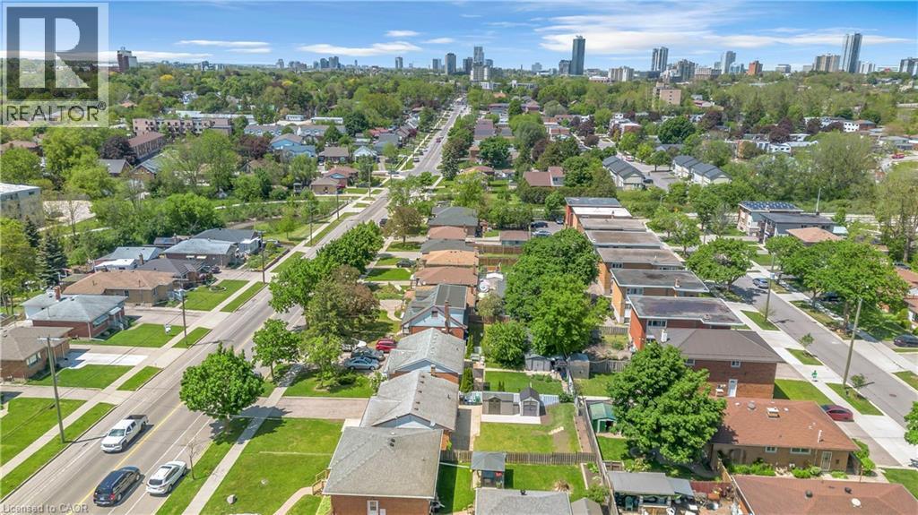 Residential neighborhood featuring mature trees, paved streets, sidewalks, and distant urban skyline - 450 Highland Road E, Kitchener, ON