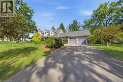 Asphalt driveway leading to a residence with a shingled roof, brick accents, and a two-car garage - 