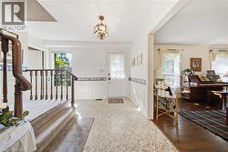 Foyer featuring a decorative overhead light fixture, white wainscoting, and patterned tile flooring - 