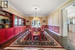 Formal dining area featuring hardwood flooring, built-in display cabinetry, crown molding, and a decorative ceiling medallion with a chandelier - 