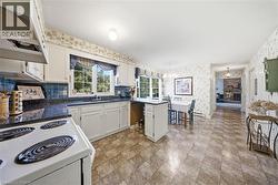 Kitchen with white cabinetry, dark countertops, a blue tiled backsplash, and patterned flooring - 
