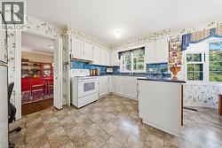 Kitchen featuring white cabinetry, tile backsplash, laminate flooring, and an integrated kitchen island with a countertop - 