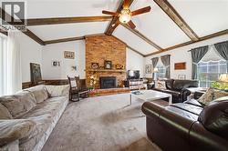 Vaulted ceiling with exposed wood beams, brick fireplace with hearth, and wall-mounted ceiling fan - 