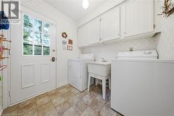 Laundry area featuring white cabinetry, a built-in utility sink, and tile flooring - 