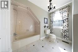 Full bathroom featuring a tub/shower combination with wall-mounted fixtures, a single-pane window, and a chandelier-style light fixture - 